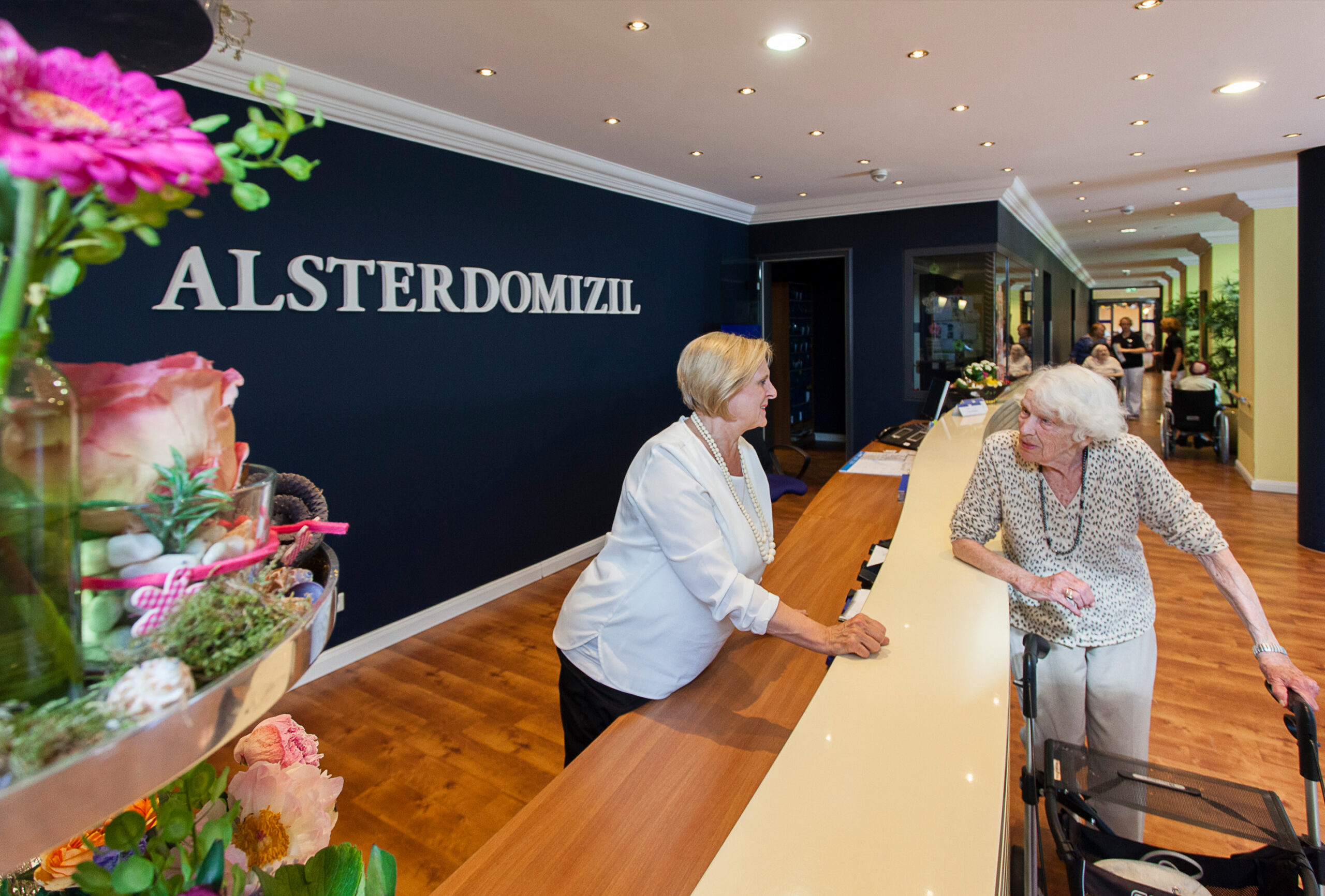 Eine Rezeptionsmitarbeiterin spricht mit einer Bewohnerin des Alsterdomizils in Wellingsbüttel.