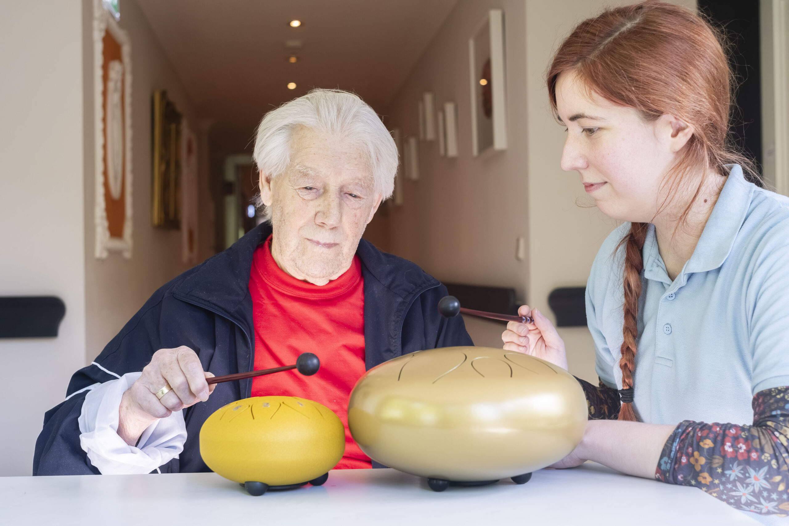 Eine Pflegekraft und ein Bewohner bei der Klangtherapie im Demenzbereich.