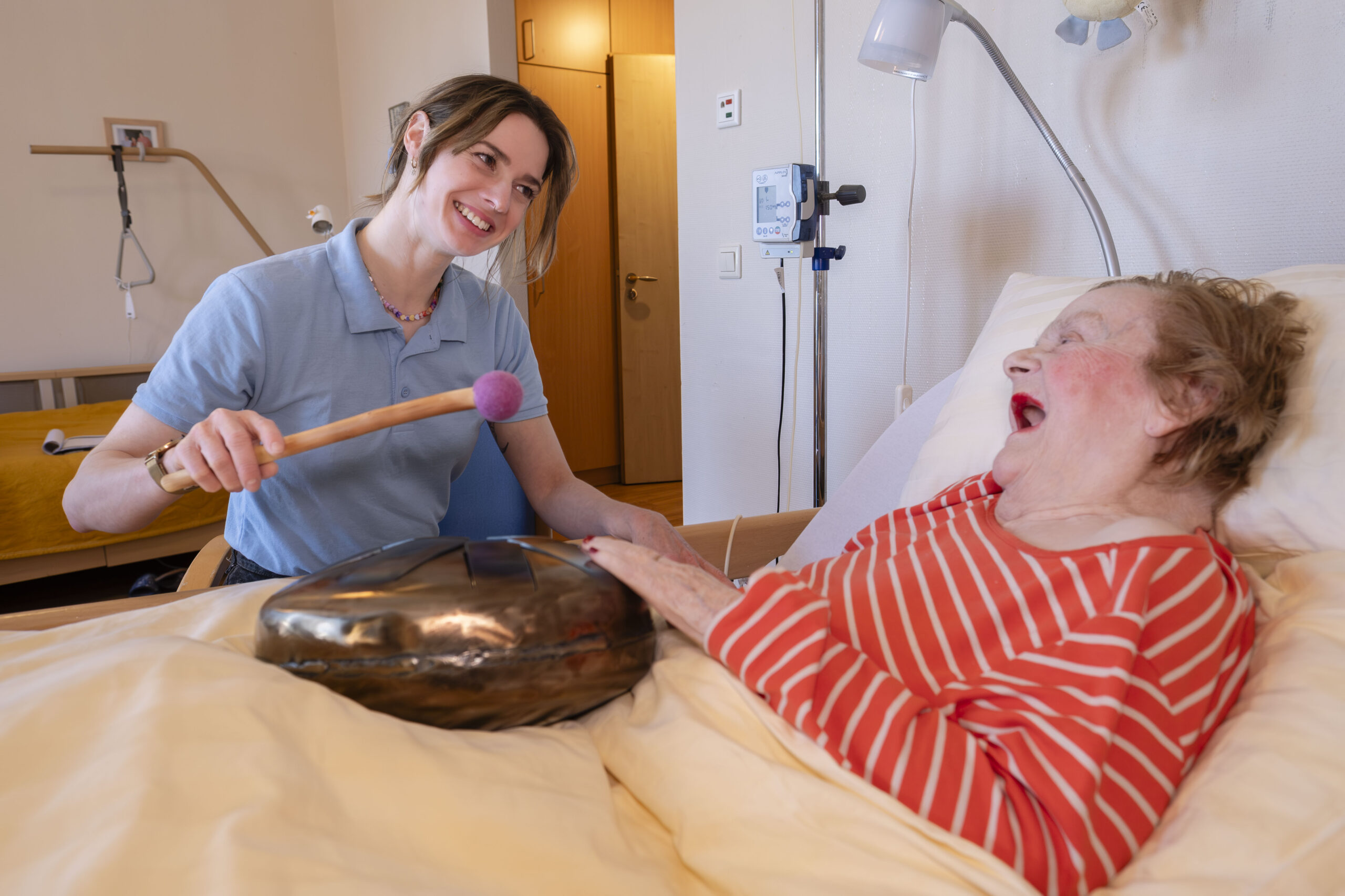 Demente Bewohnerin und Betreuungskraft bei der Musiktherapie im Bewohnerzimmer.