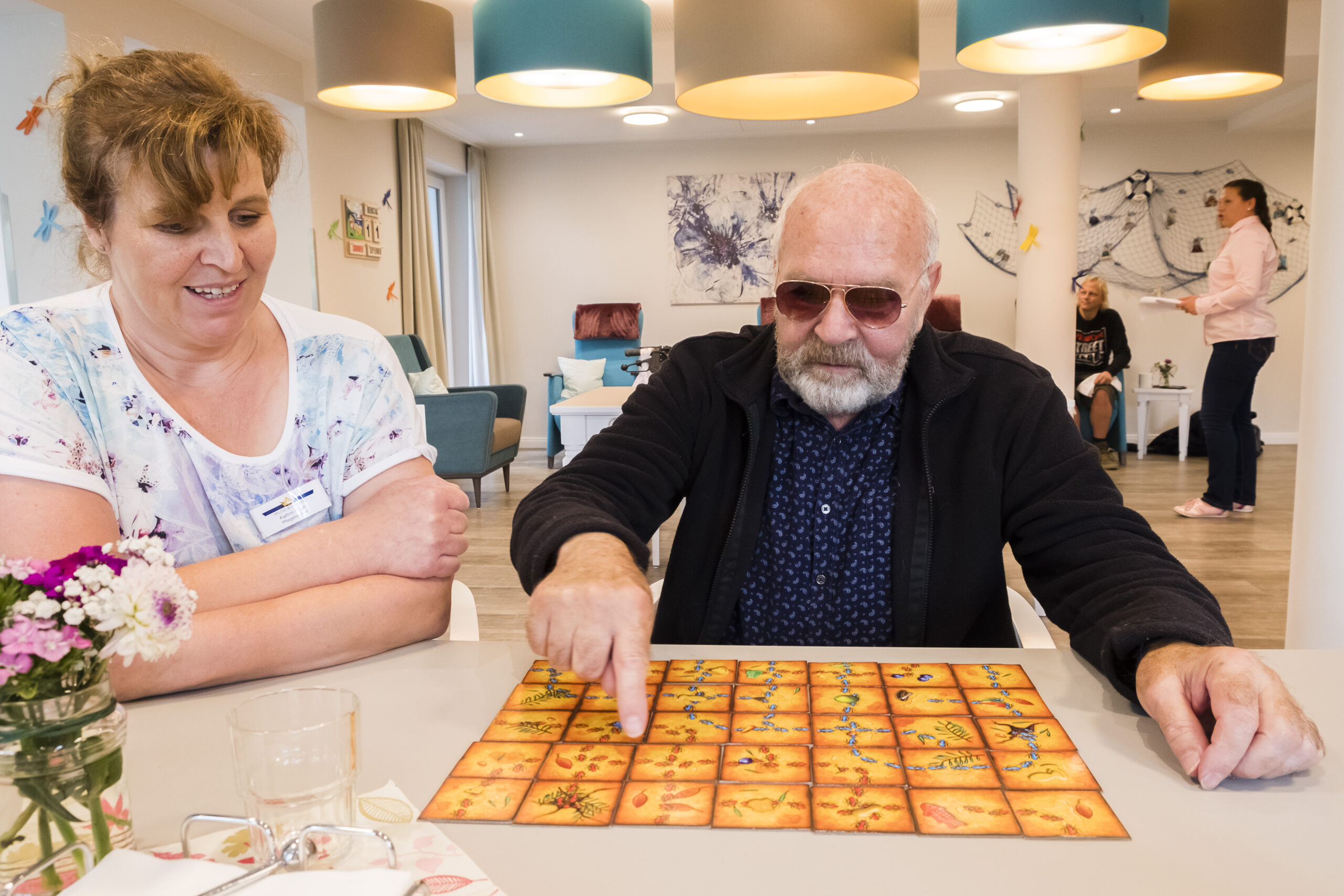 Betreuung und Bewohner beim spielen eines Brettspiels.