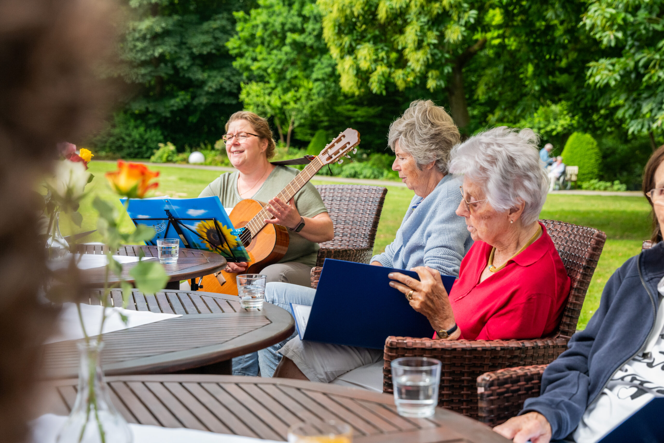 Besucher des Tagesdomizils sitzen auf der Terrasse und musizieren.